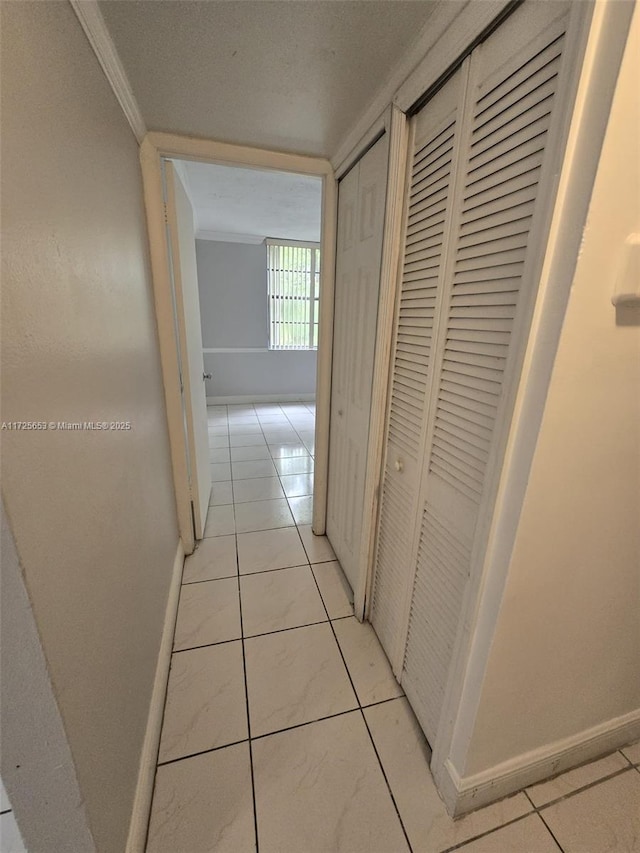 hallway with light tile patterned floors and crown molding