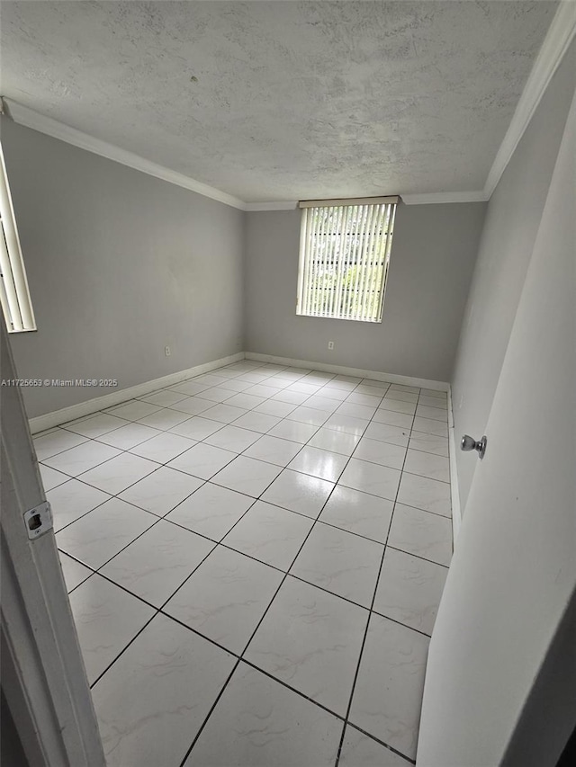 empty room with a textured ceiling, light tile patterned floors, and ornamental molding