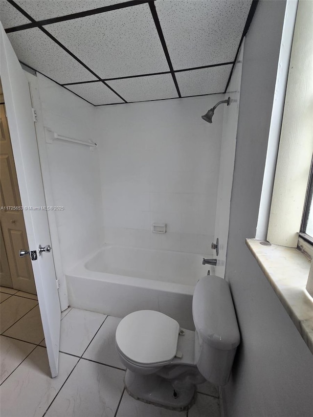 bathroom with shower / bathtub combination, a drop ceiling, toilet, and tile patterned flooring