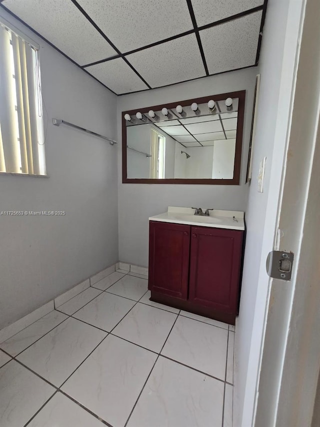 bathroom with a paneled ceiling, tile patterned floors, and vanity