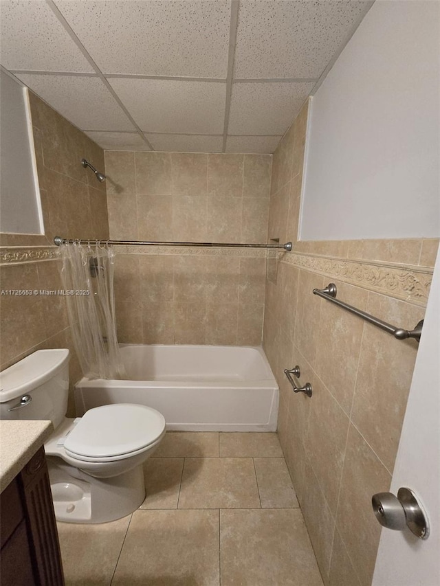 full bathroom featuring toilet, tile patterned flooring, tile walls, a drop ceiling, and vanity