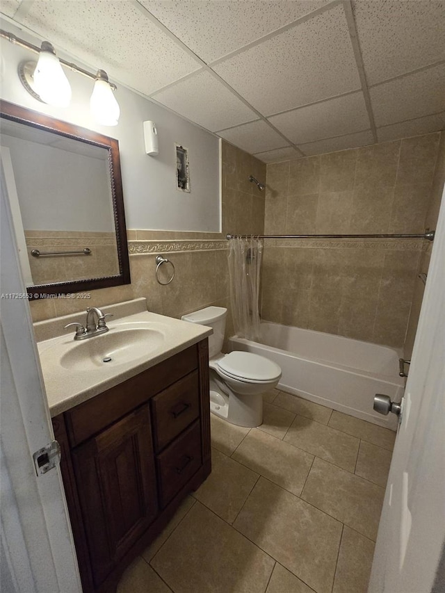 full bathroom with shower / bath combo, a paneled ceiling, tile patterned flooring, tile walls, and vanity