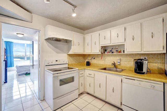 kitchen with sink, white appliances, tasteful backsplash, a textured ceiling, and light tile patterned flooring