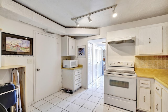 kitchen with light tile patterned floors, backsplash, and white appliances