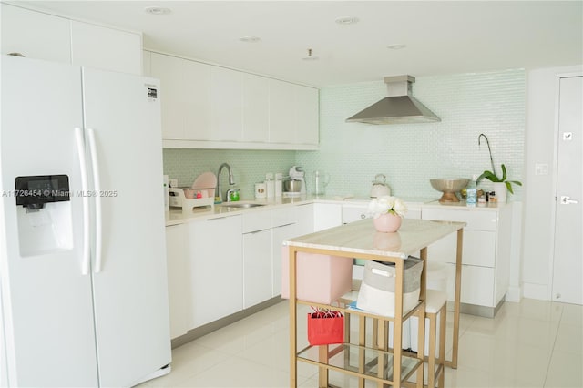 kitchen with sink, wall chimney exhaust hood, white cabinets, and white fridge with ice dispenser