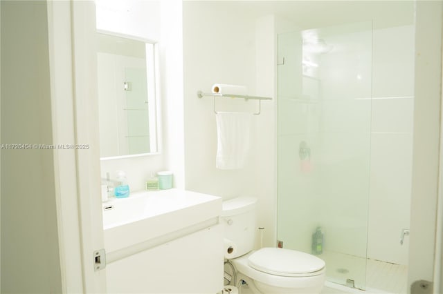 bathroom with a shower with door, vanity, and toilet