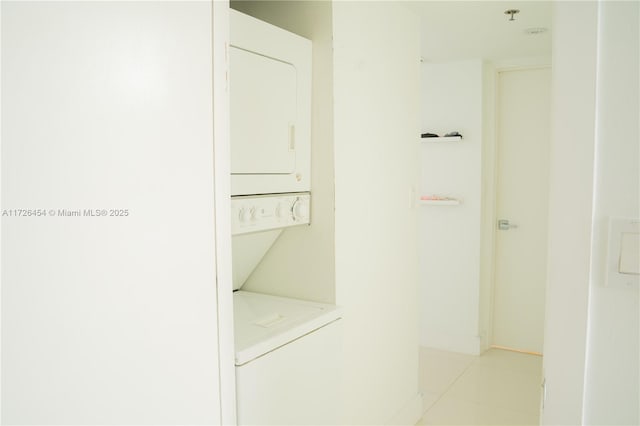 interior space featuring light tile patterned flooring and stacked washer / dryer