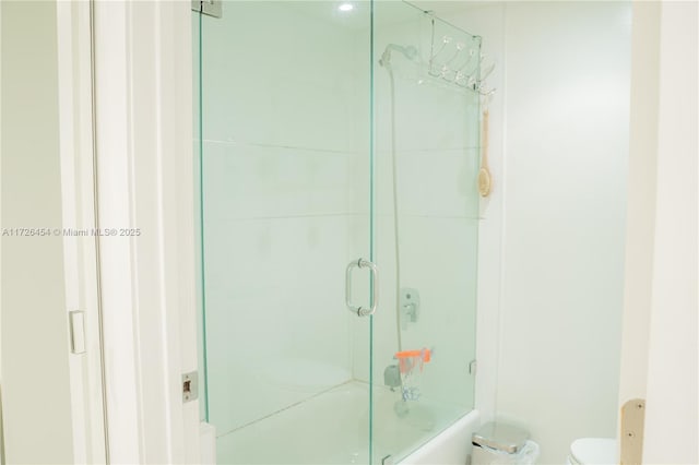 bathroom with toilet and bath / shower combo with glass door