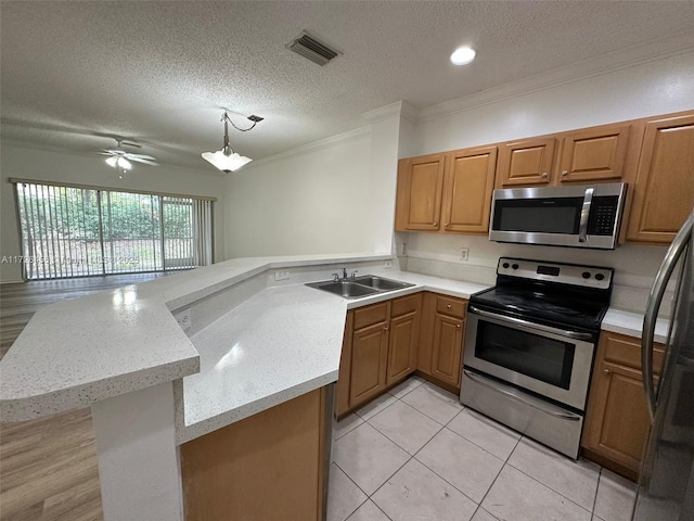 kitchen with a textured ceiling, stainless steel appliances, sink, and kitchen peninsula