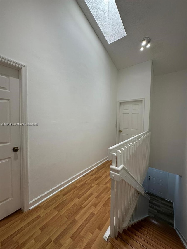 staircase featuring hardwood / wood-style floors and vaulted ceiling with skylight