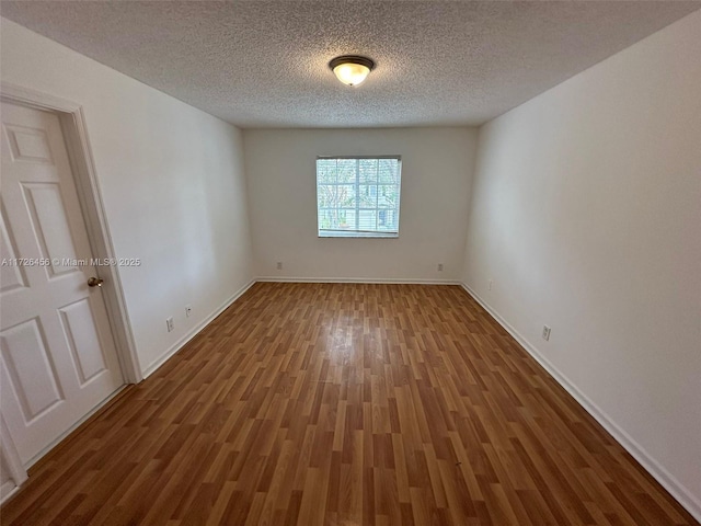 spare room featuring a textured ceiling and hardwood / wood-style floors