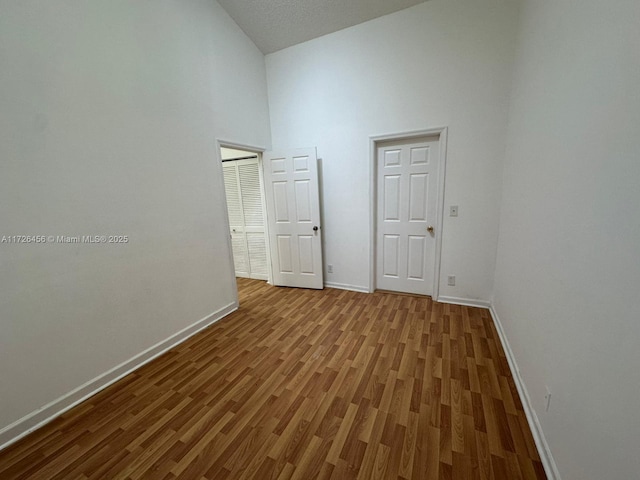 spare room featuring high vaulted ceiling and wood-type flooring