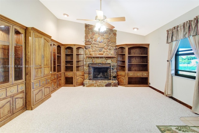 living room with vaulted ceiling, a stone fireplace, light colored carpet, and ceiling fan