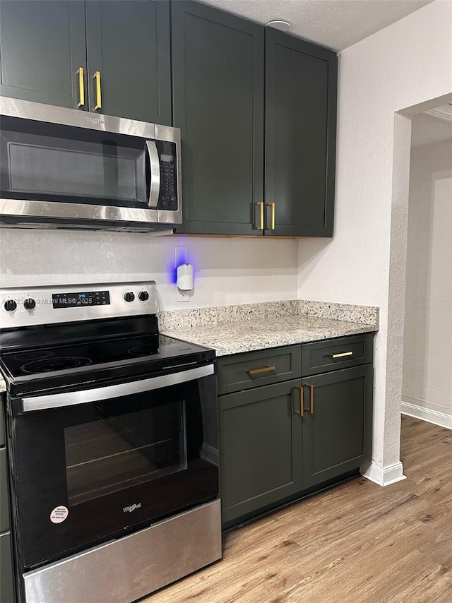 kitchen featuring light stone countertops, light hardwood / wood-style floors, and appliances with stainless steel finishes