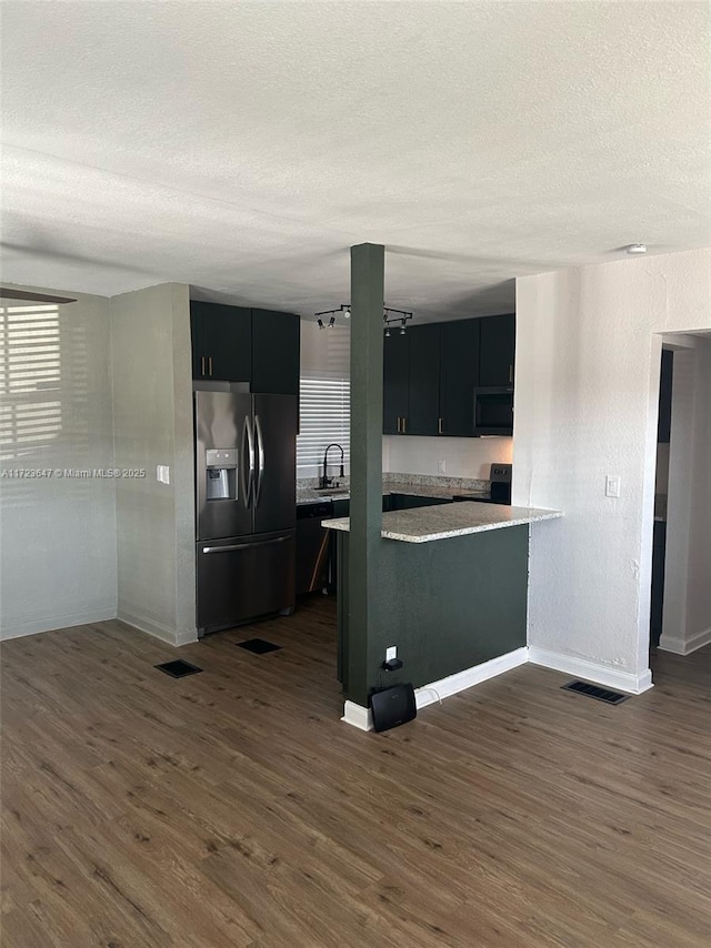 kitchen featuring kitchen peninsula, dark wood-type flooring, a textured ceiling, stainless steel fridge with ice dispenser, and sink