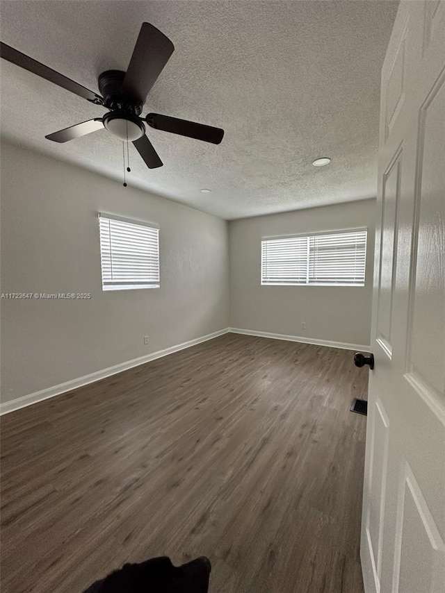 unfurnished room featuring dark hardwood / wood-style flooring, a textured ceiling, ceiling fan, and a wealth of natural light