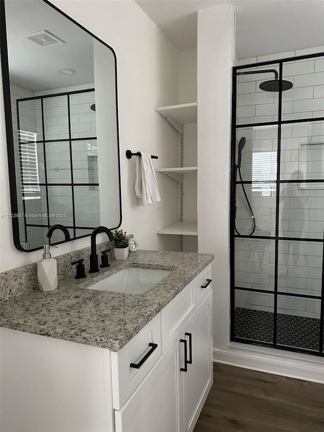 bathroom with walk in shower, wood-type flooring, and vanity