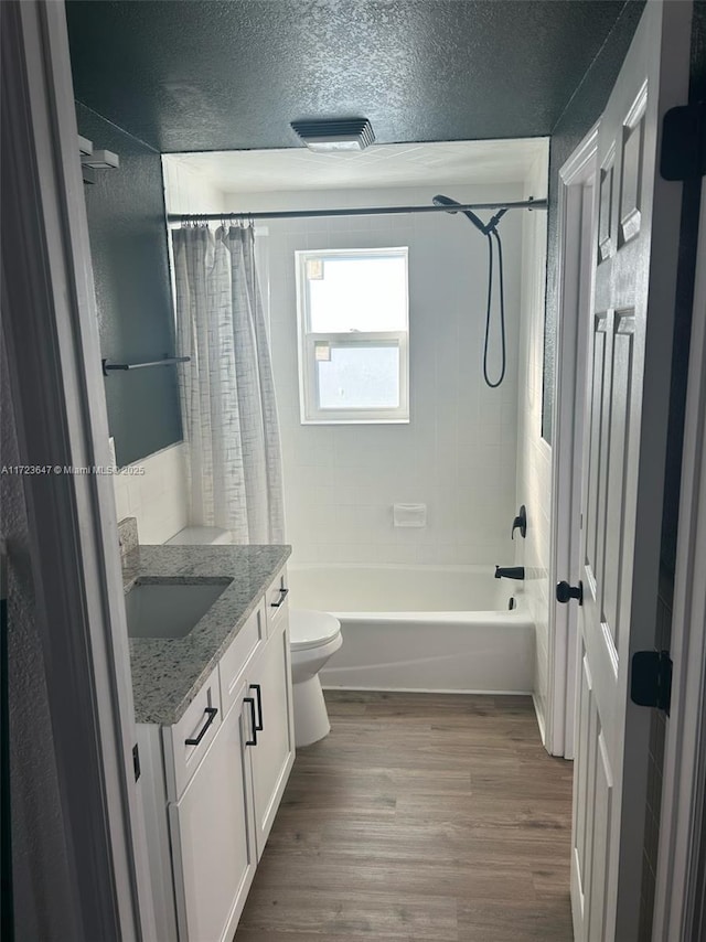 full bathroom with a textured ceiling, toilet, wood-type flooring, shower / bath combination with curtain, and vanity