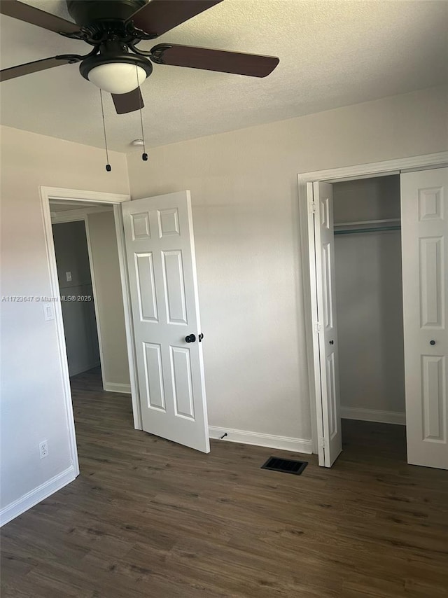 unfurnished bedroom with dark hardwood / wood-style flooring, a closet, and ceiling fan