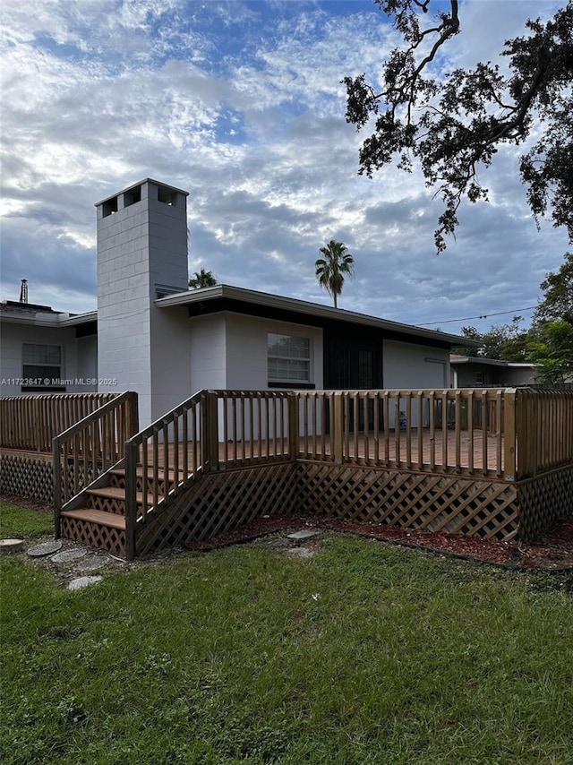 rear view of property with a deck and a yard