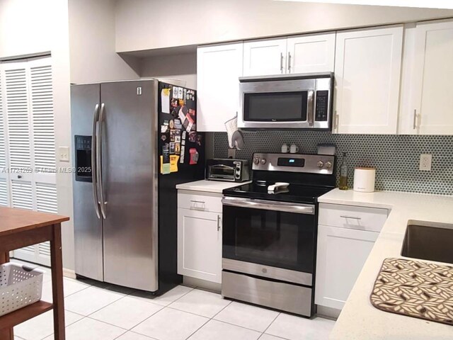 kitchen with tasteful backsplash, stainless steel appliances, light tile patterned floors, and white cabinets