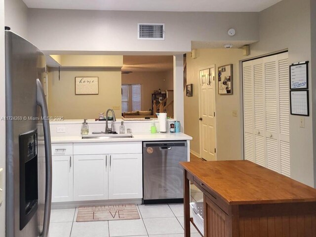 kitchen featuring sink, light tile patterned floors, white cabinets, and appliances with stainless steel finishes