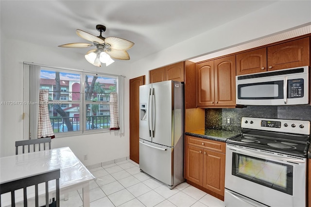 kitchen with ceiling fan, dark stone countertops, light tile patterned floors, decorative backsplash, and appliances with stainless steel finishes