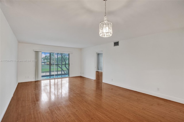 unfurnished room with a notable chandelier and hardwood / wood-style floors