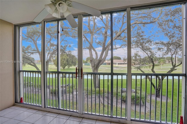 unfurnished sunroom featuring ceiling fan and a water view