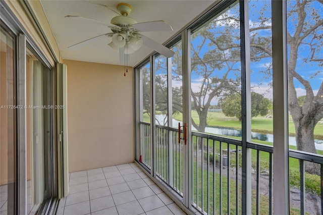 unfurnished sunroom featuring ceiling fan and a water view