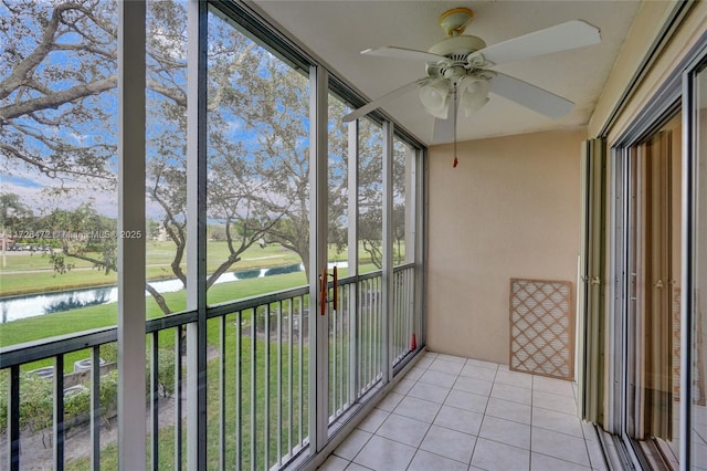 unfurnished sunroom featuring ceiling fan and a water view