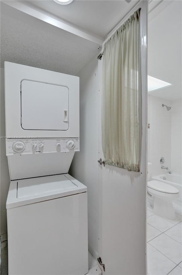 laundry area featuring stacked washer and clothes dryer and light tile patterned floors