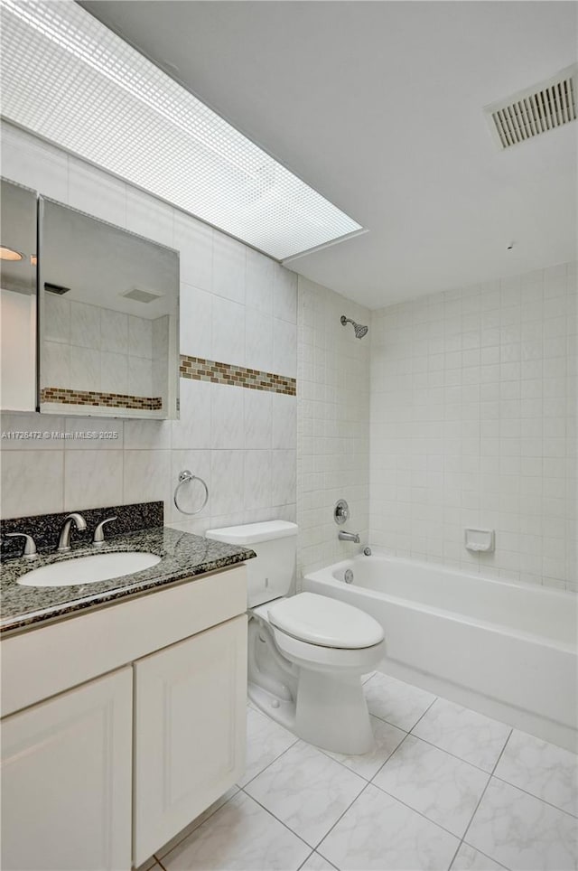 full bathroom featuring tiled shower / bath, tile patterned flooring, tile walls, toilet, and vanity