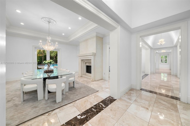 dining space featuring ornamental molding, a fireplace, a raised ceiling, and a notable chandelier