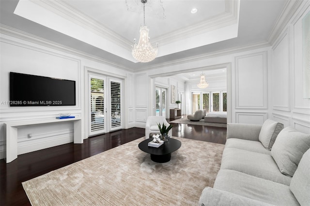 living room with dark wood-type flooring, ornamental molding, and a raised ceiling