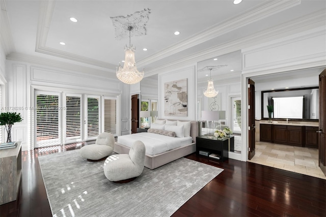 bedroom with a raised ceiling, light wood-type flooring, ensuite bathroom, and ornamental molding