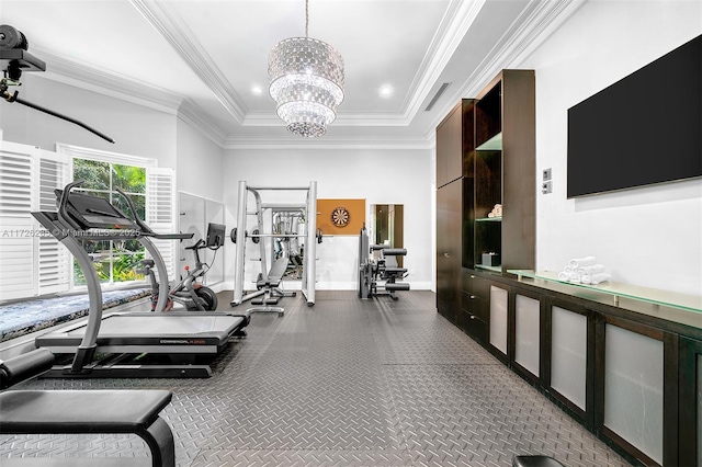 exercise room featuring crown molding, a high ceiling, a tray ceiling, and an inviting chandelier