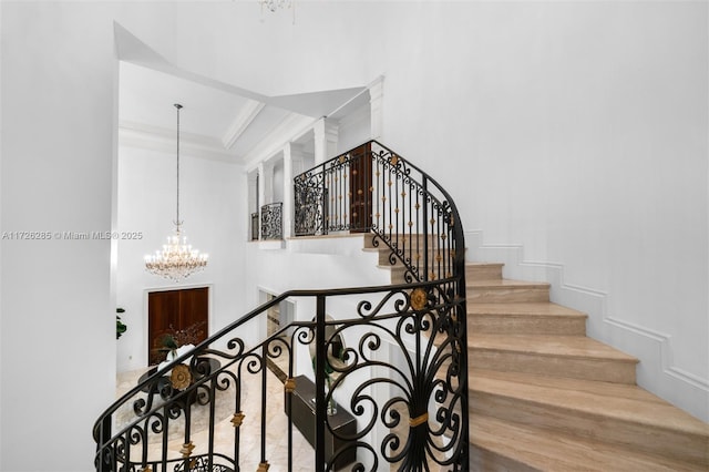 stairway featuring ornamental molding and a chandelier