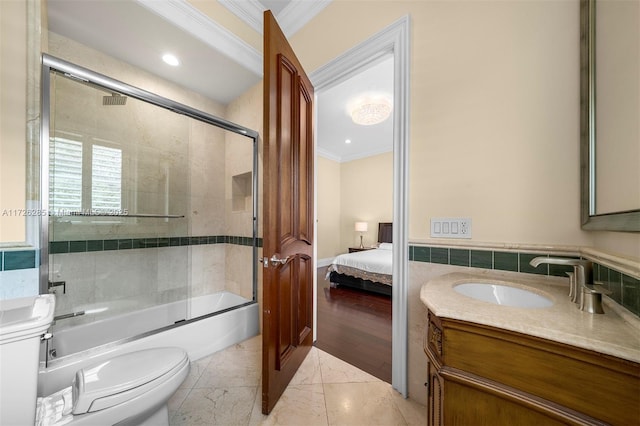 full bathroom with toilet, vanity, tile walls, crown molding, and shower / bath combination with glass door