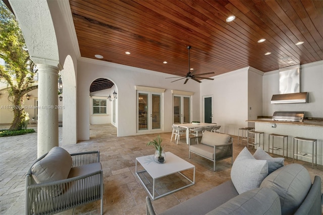 view of patio / terrace with ceiling fan, an outdoor living space, a grill, exterior kitchen, and an outdoor bar