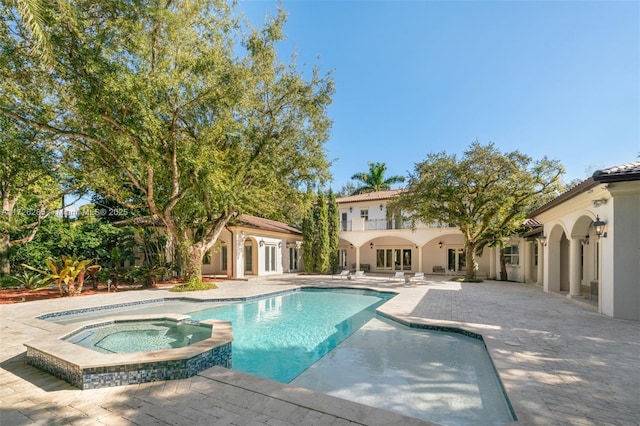 view of pool with french doors, a patio area, and an in ground hot tub