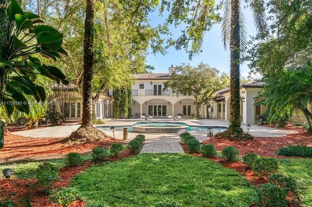 rear view of house with a pool with hot tub, a patio area, and a balcony