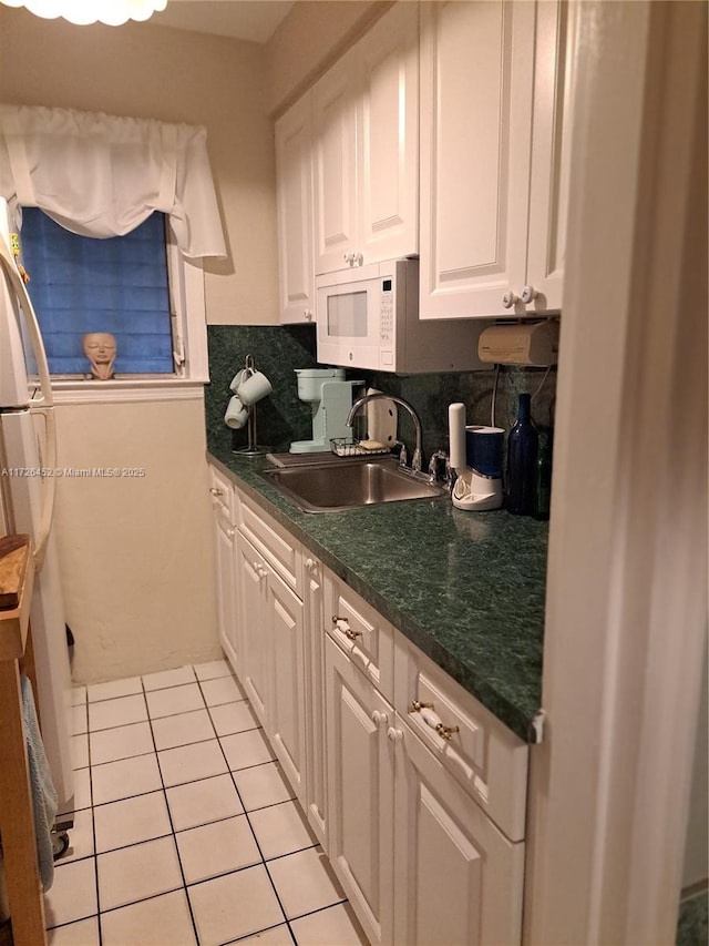 kitchen featuring sink, backsplash, light tile patterned floors, and white cabinetry