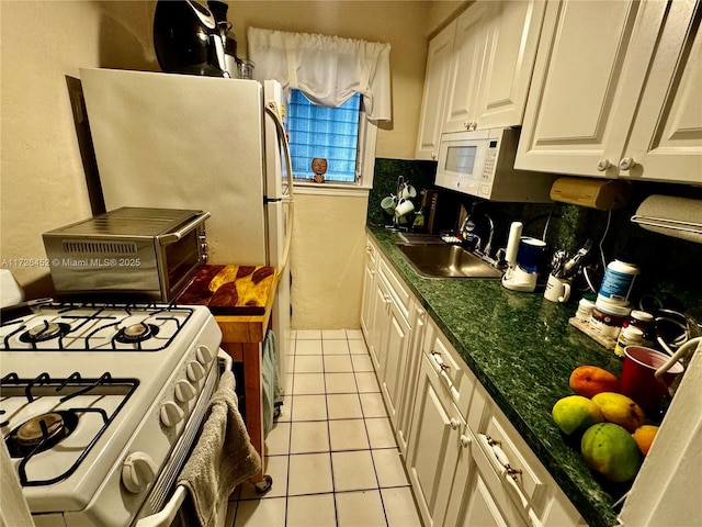 kitchen with sink, white appliances, light tile patterned floors, and white cabinets