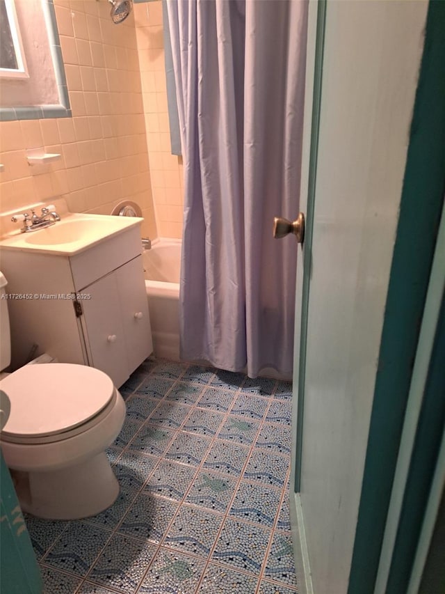 full bathroom with toilet, shower / tub combo, vanity, and tile walls