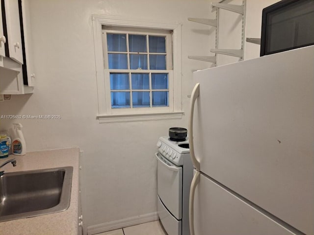 kitchen featuring white appliances, white cabinets, light tile patterned flooring, and sink