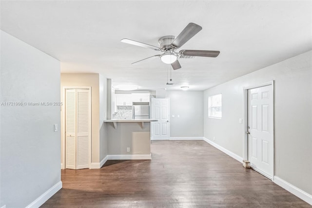 unfurnished living room featuring ceiling fan and dark hardwood / wood-style floors