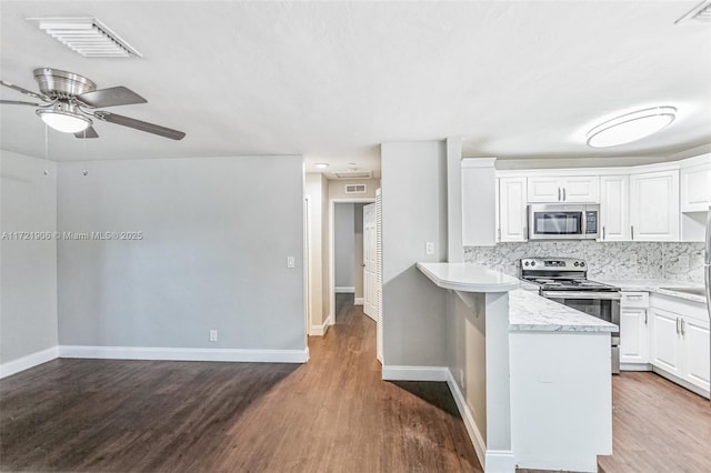 kitchen with hardwood / wood-style floors, stainless steel appliances, decorative backsplash, and white cabinetry