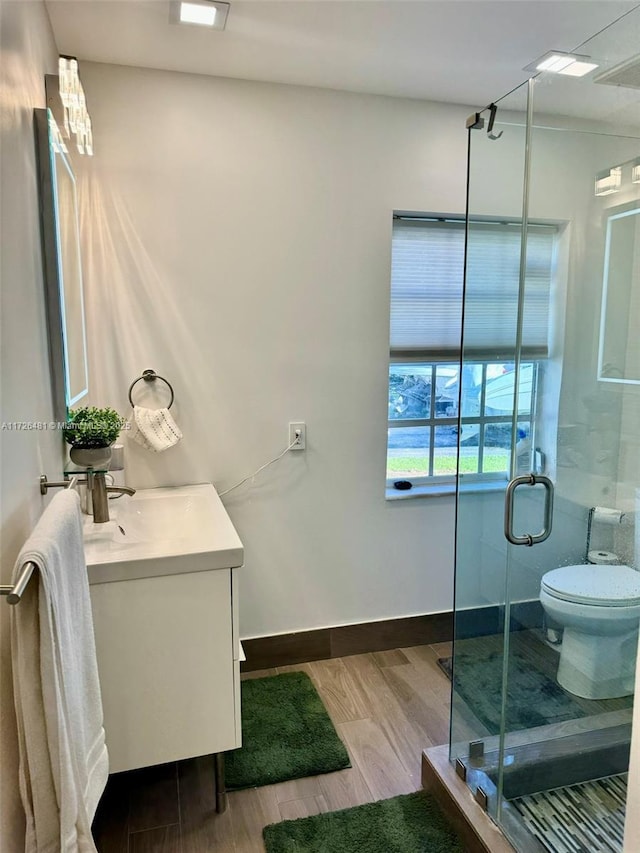 bathroom featuring toilet, vanity, a shower with door, and hardwood / wood-style flooring