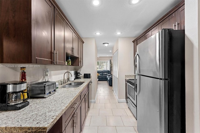 kitchen featuring sink, stainless steel appliances, light tile patterned flooring, and light stone counters